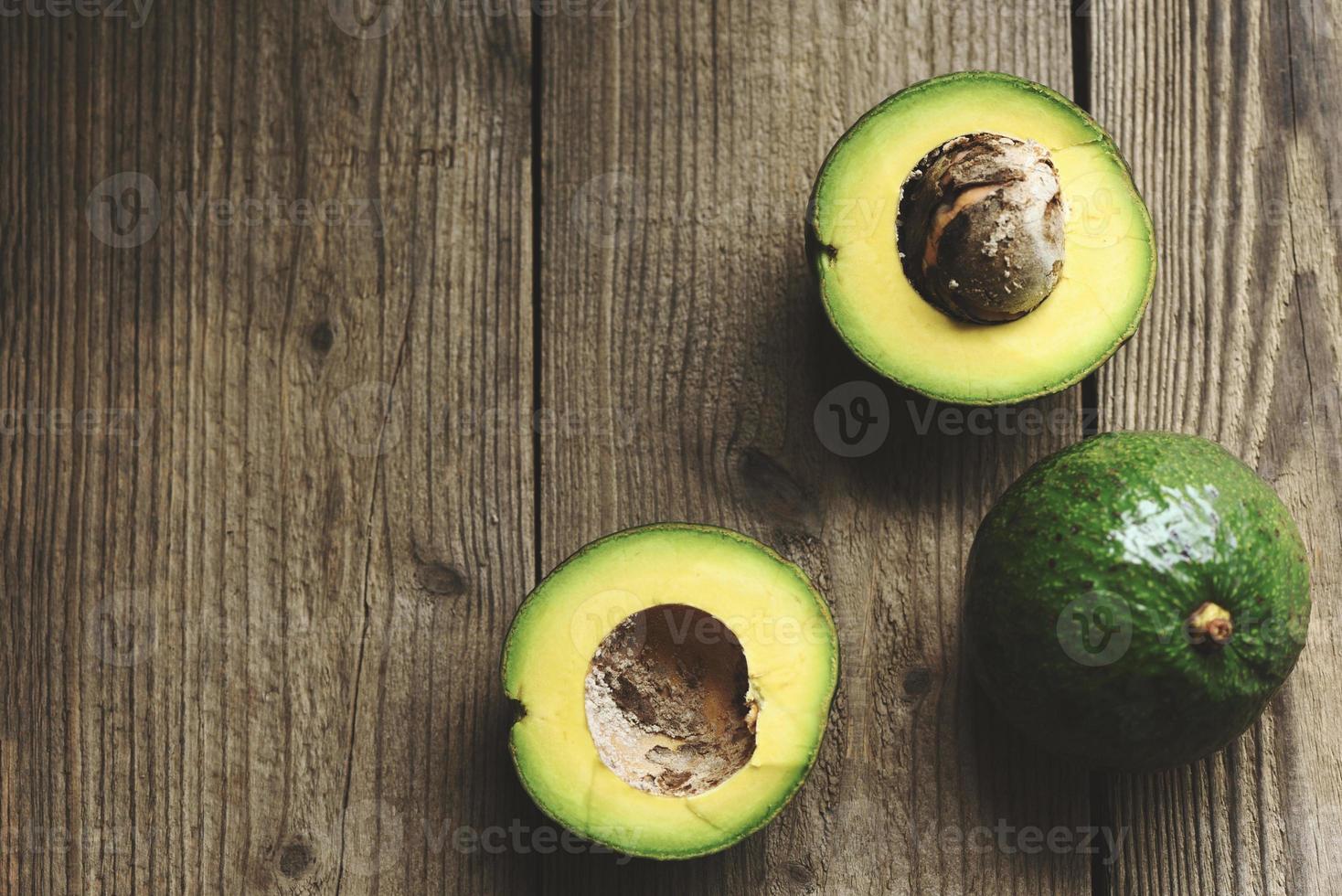 avocado e fetta tagliati a metà avocado su sfondo di legno, frutta cibo sano concept foto