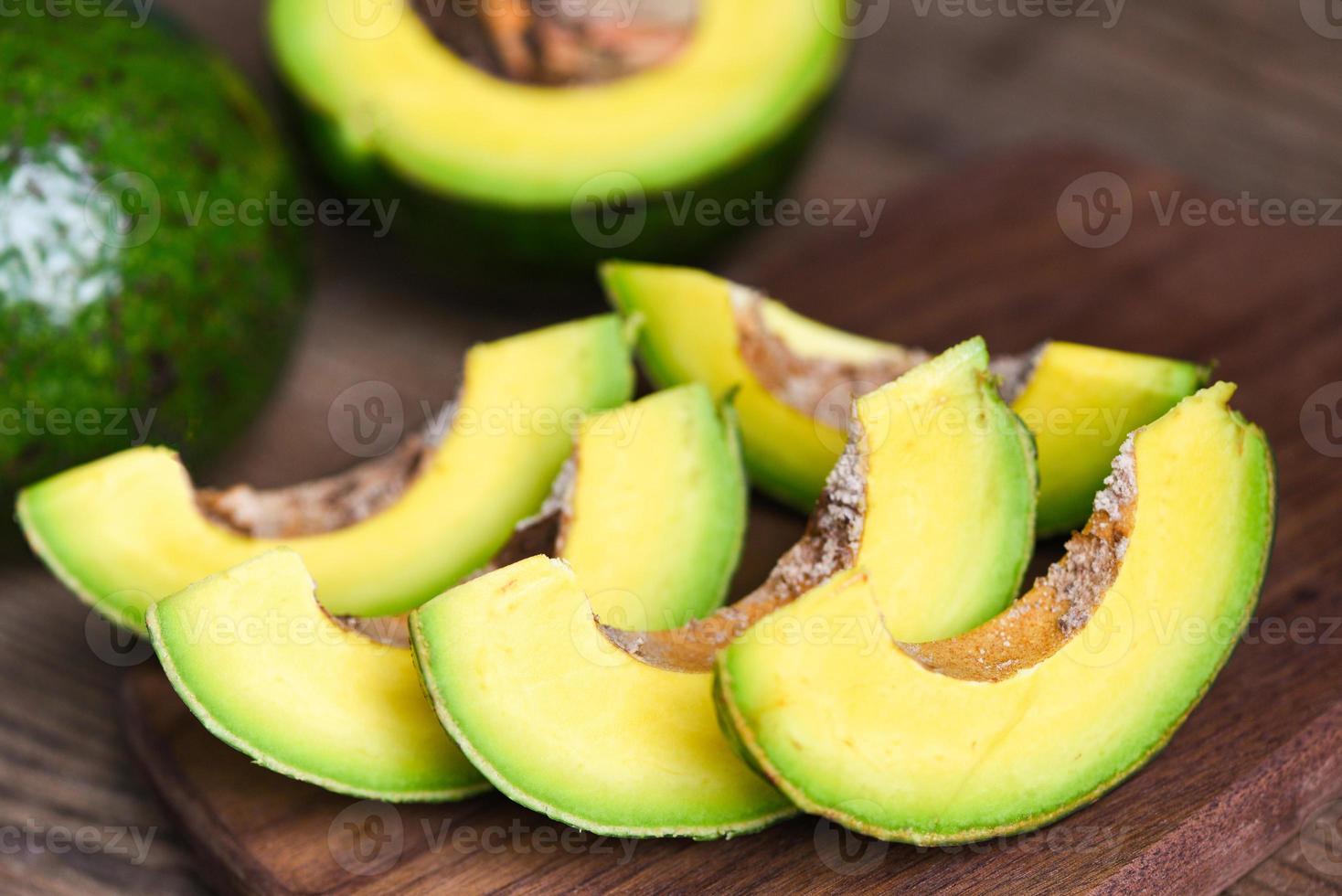 frutto di avocado e fetta di avocado su sfondo di legno, concetto di cibo sano di frutta. foto