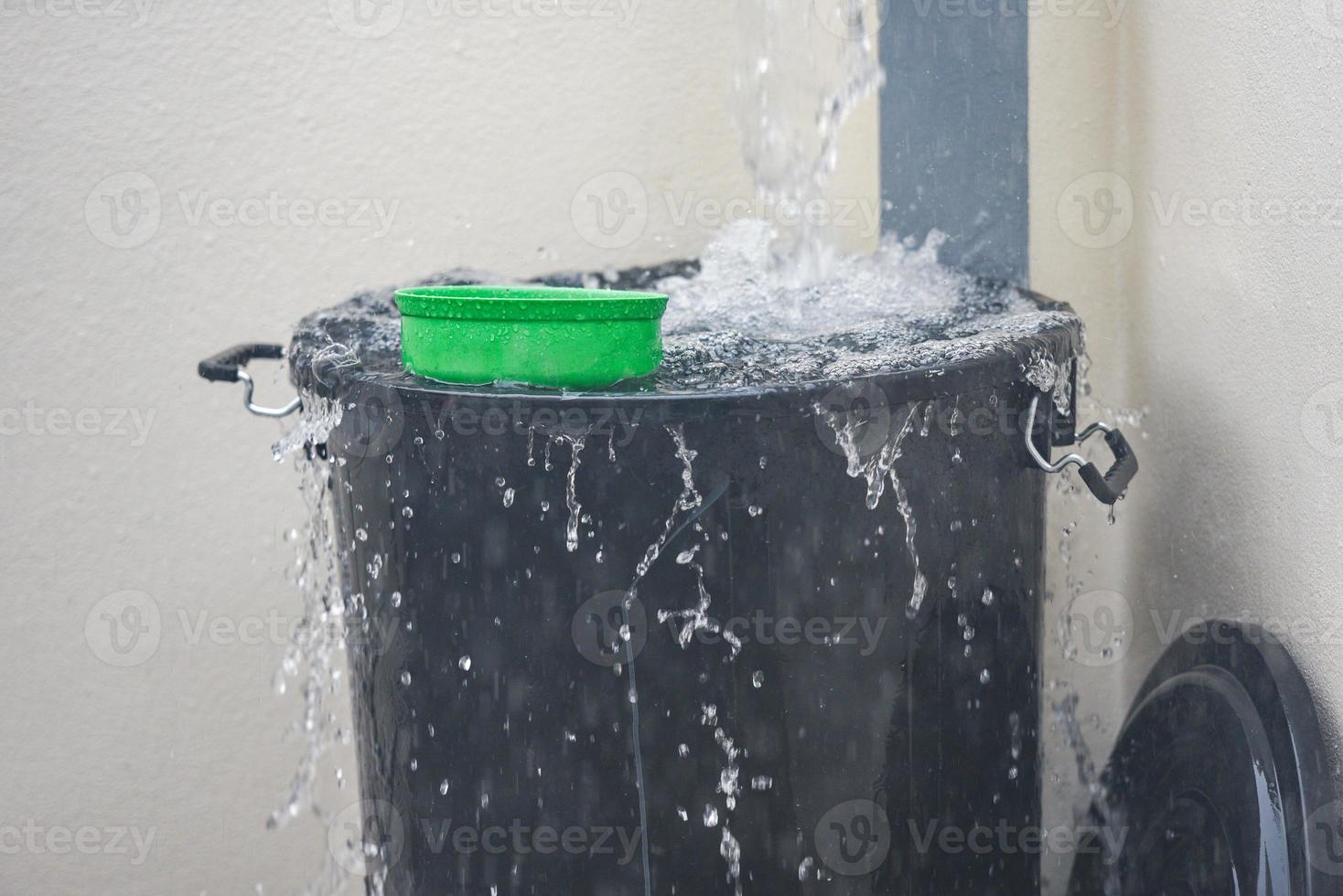 secchio con spruzzi d'acqua raccolta dell'acqua piovana nel secchio d'acqua dopo la pioggia foto