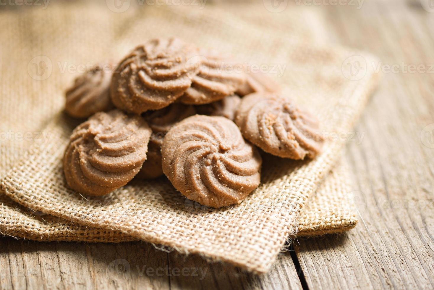 biscotti al cioccolato sul sacco e fondo in legno, mini biscotti biscotti. foto