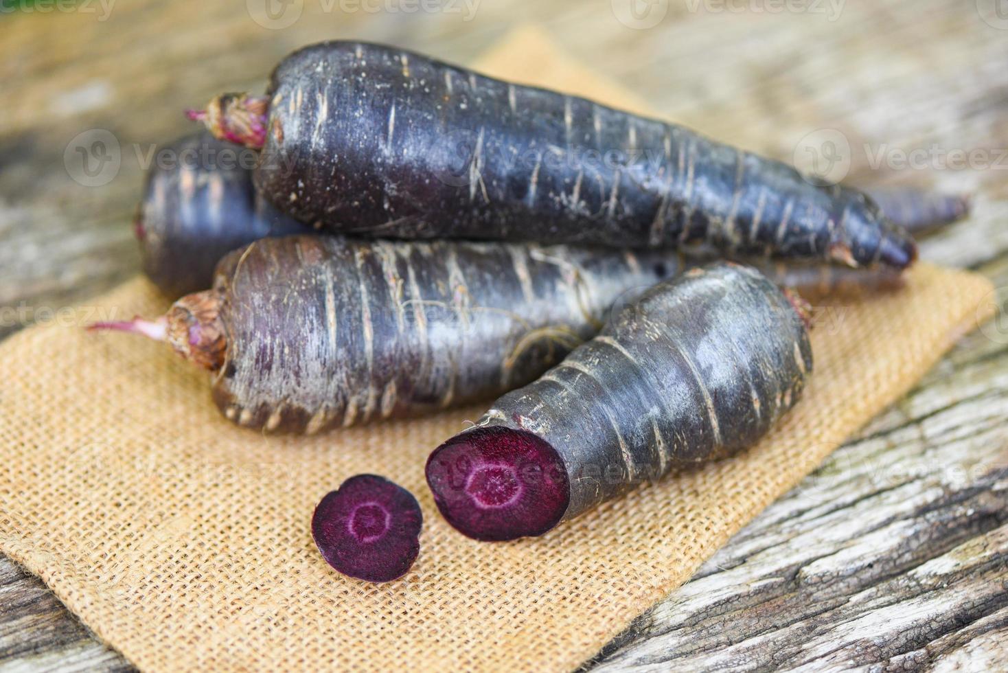 carota viola sul sacco, carota fresca per cucinare vegetariano su tavola di legno. foto