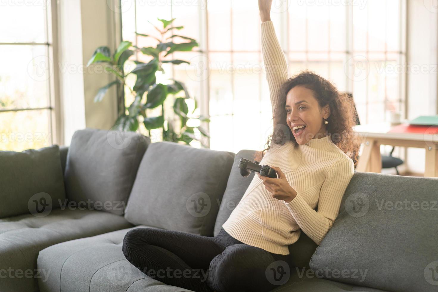 donna latina che gioca ai videogiochi con le mani che tengono il joystick foto