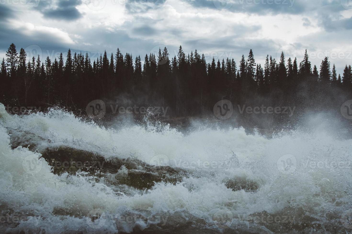 onde e spruzzi di fiume di montagna sullo sfondo della foresta e del cielo drammatico. paesaggio dell'acqua del fiume della foresta. foto