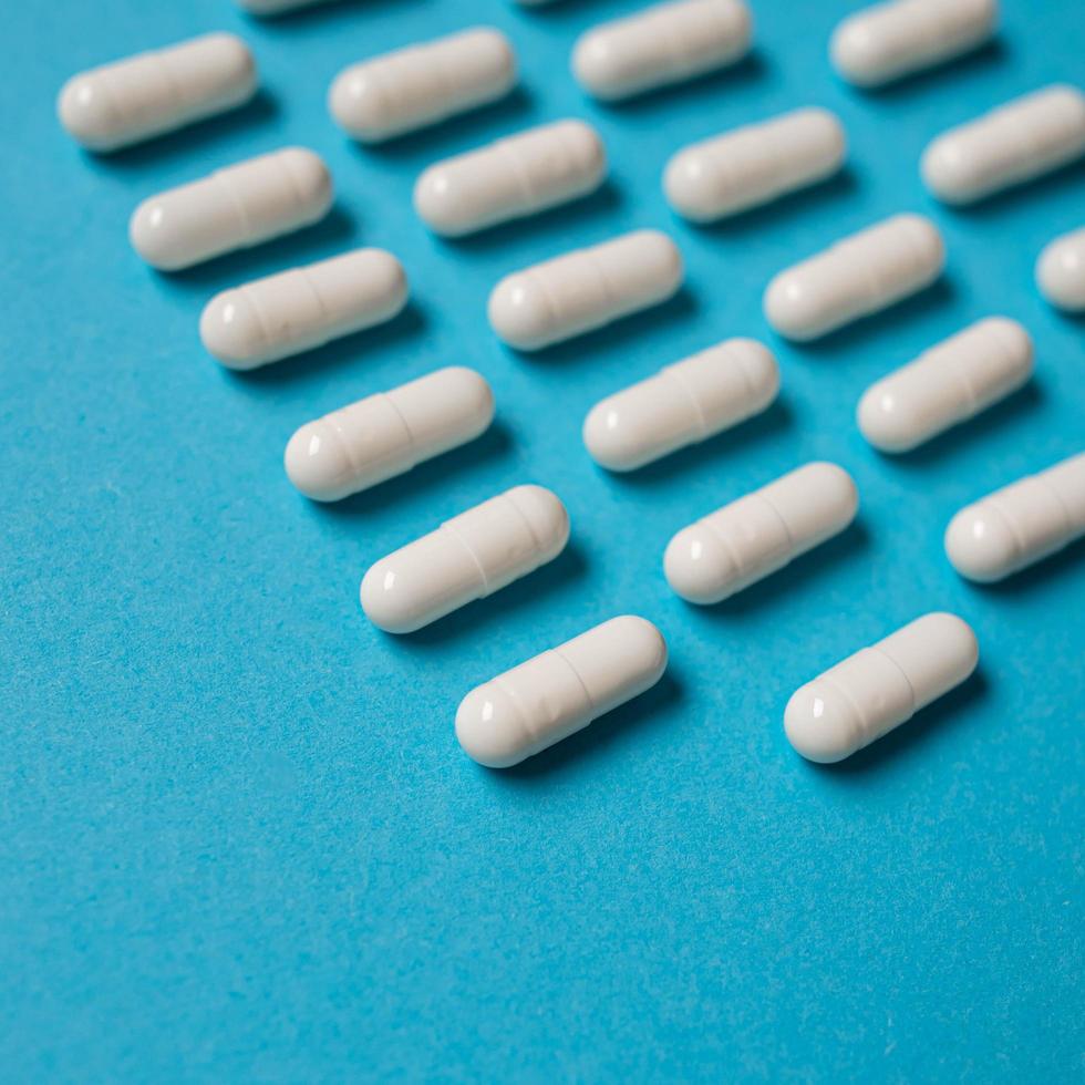 molte pillole di capsule bianche su uno sfondo colorato. integratori e medicinali per la salute foto