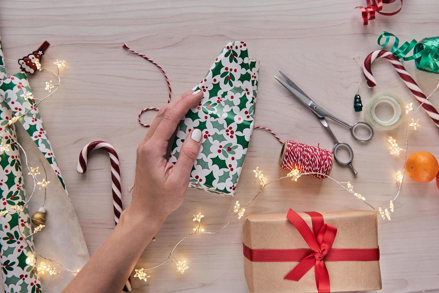 composizione di natale. scatole regalo, regali incartati con carta e nastro, luci, bastoncini di zucchero su fondo di legno. Holdiay fai da te decorazioni per la casa fatte a mano. inverno, capodanno disteso, vista dall'alto foto