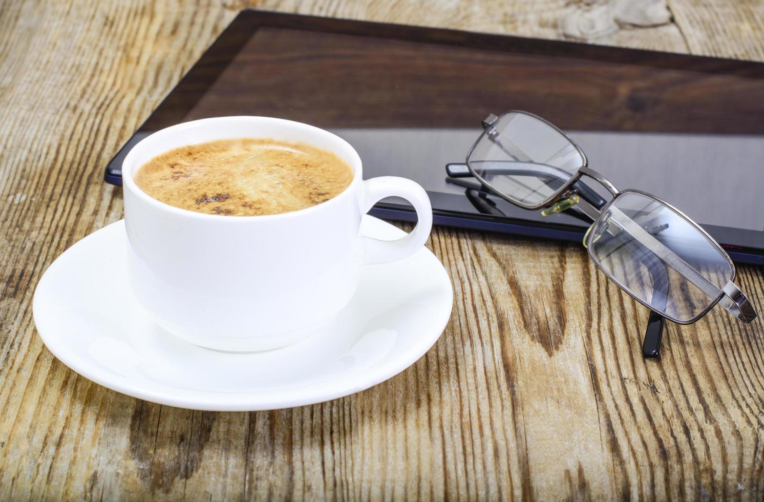 computer portatile, caffè e occhiali da sole dell'uomo d'affari sul posto di lavoro foto