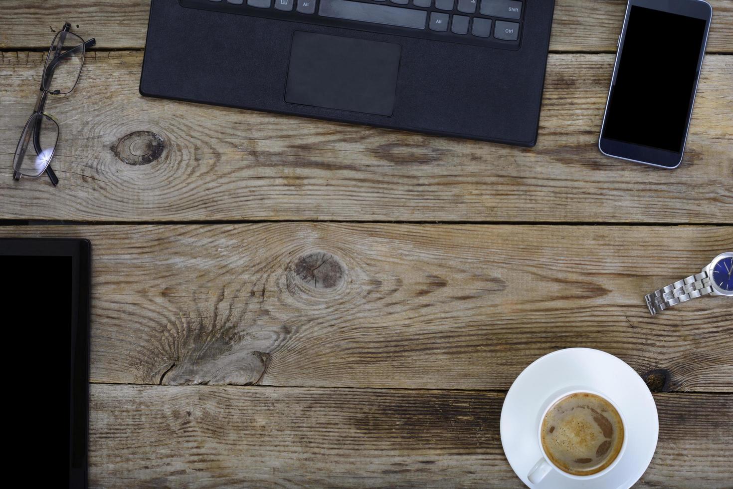 posto di lavoro più conveniente per l'uomo d'affari, laptop, telefono, caffè e bicchieri sul tavolo in legno foto