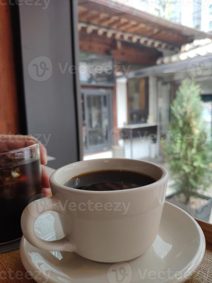 caffè nero in una tazza su uno sfondo di piante foto