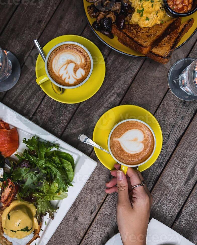 due caffè latte in una tazza con del cibo accanto foto