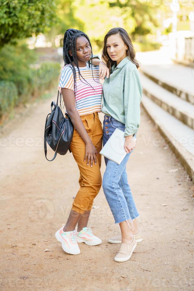 due donne multietniche che posano insieme con abiti casual colorati foto