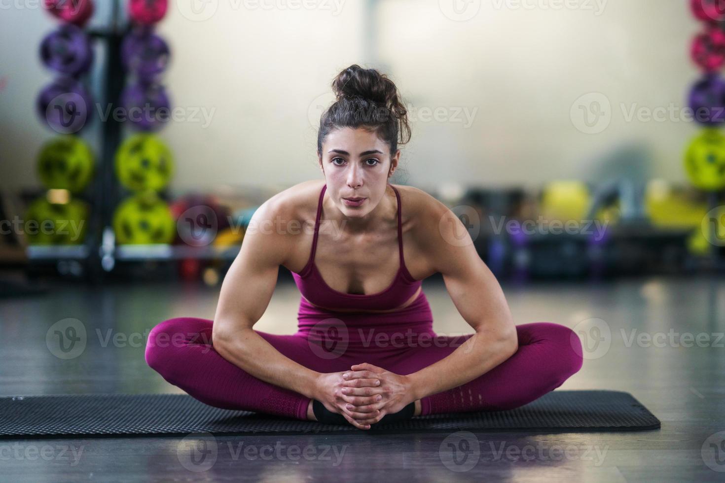 giovane donna che fa esercizi di stretching su un tappetino da yoga foto