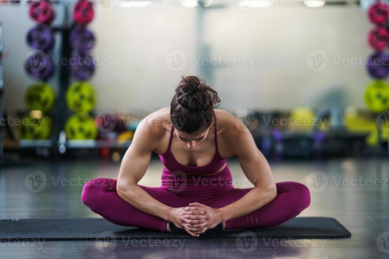 giovane donna che fa esercizi di stretching su un tappetino da yoga foto