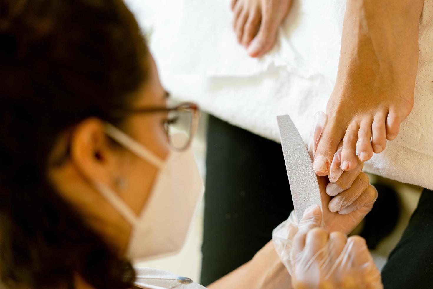 estetista che fa una pedicure dipingendo le unghie della sua cliente in un centro estetico. foto