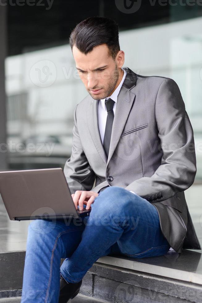 giovane imprenditore digitando in un computer portatile in background urbano foto