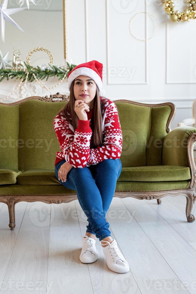 giovane donna seduta sul divano da sola in un soggiorno decorato per il natale foto