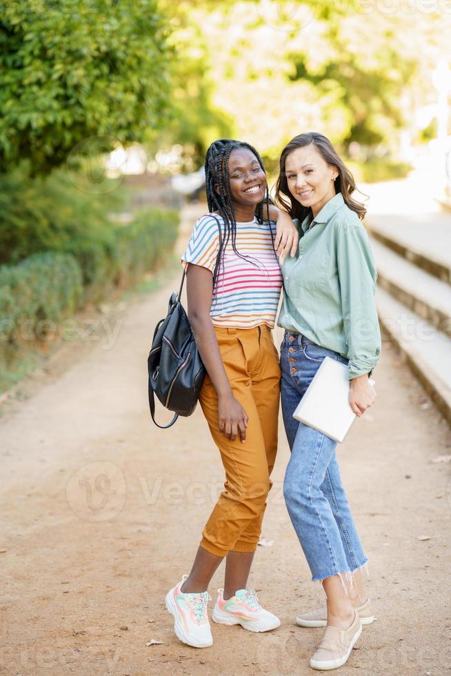 due donne multietniche che posano insieme con abiti casual colorati foto