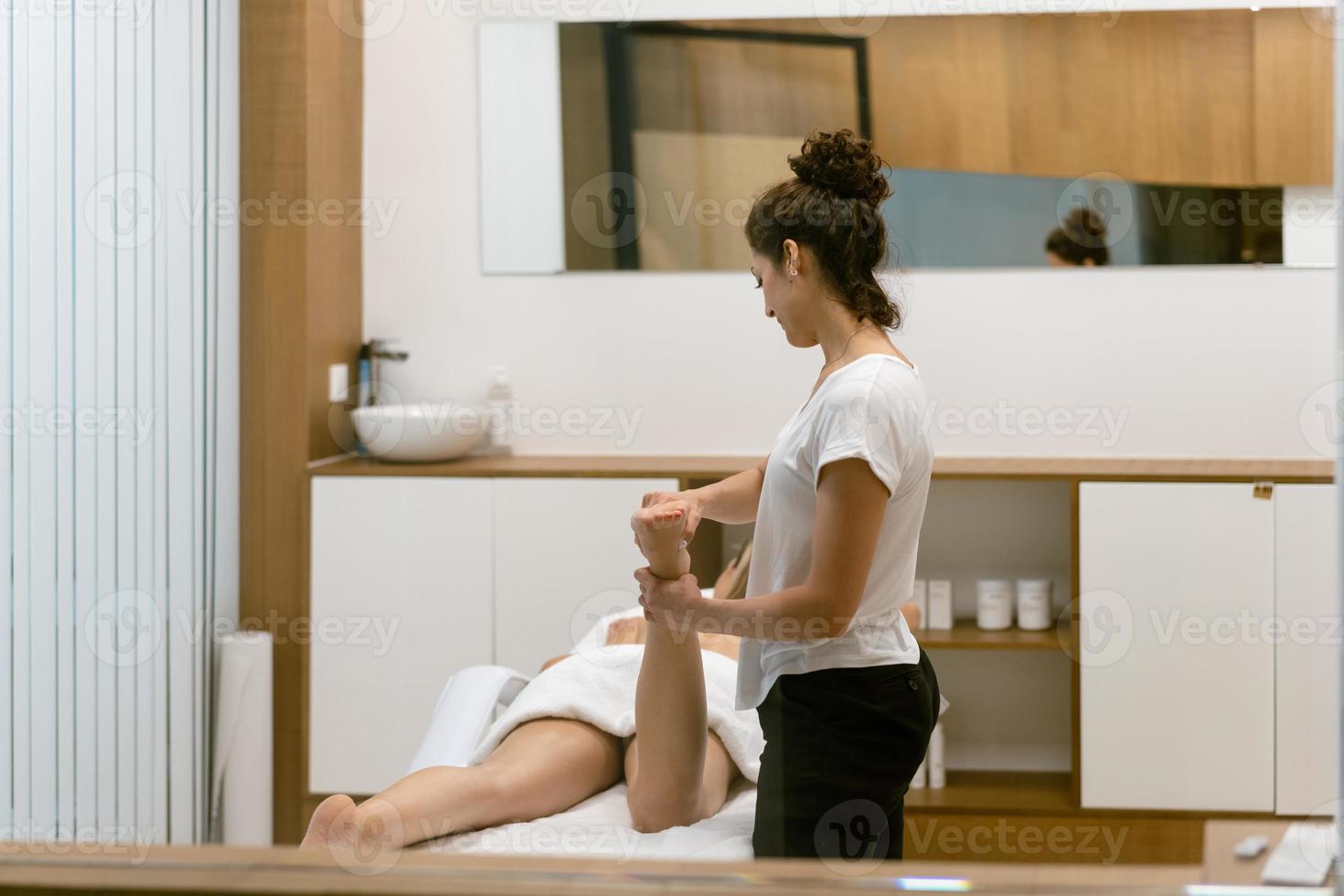 donna di mezza età che fa un massaggio alle gambe in un salone di bellezza. foto