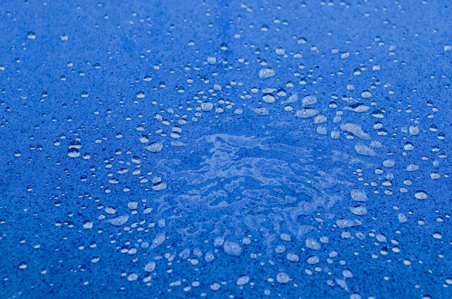 tessuto blu scuro astratto gocce d'acqua pieghe colorate frammento superficie strutturata su tela blu. foto