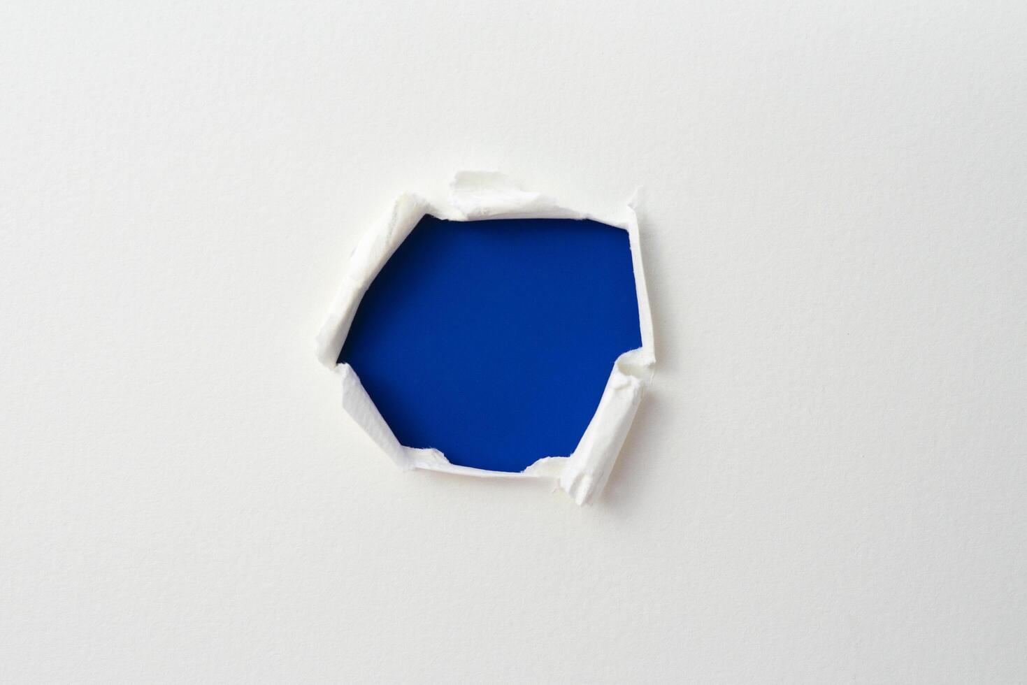 cornice di carta strappata con i lati strappati. un buco blu di strappato sulla carta bianca. carta strappata realistica con i bordi strappati per lo spazio della copia e il testo. foto