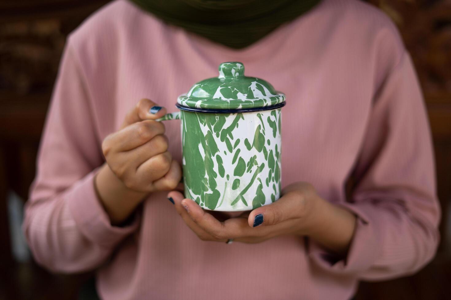 una tazza di caffè caldo è sul tavolo. una ragazza tiene in mano una bevanda gustosa. una sorta di godersi il tempo libero. foto