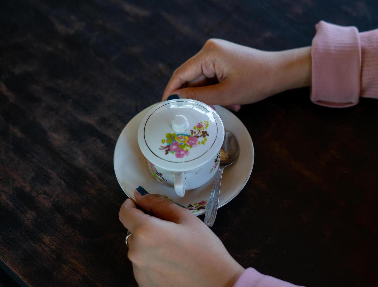 una tazza di caffè caldo è sul tavolo. una ragazza tiene in mano una bevanda gustosa. una sorta di godersi il tempo libero. foto