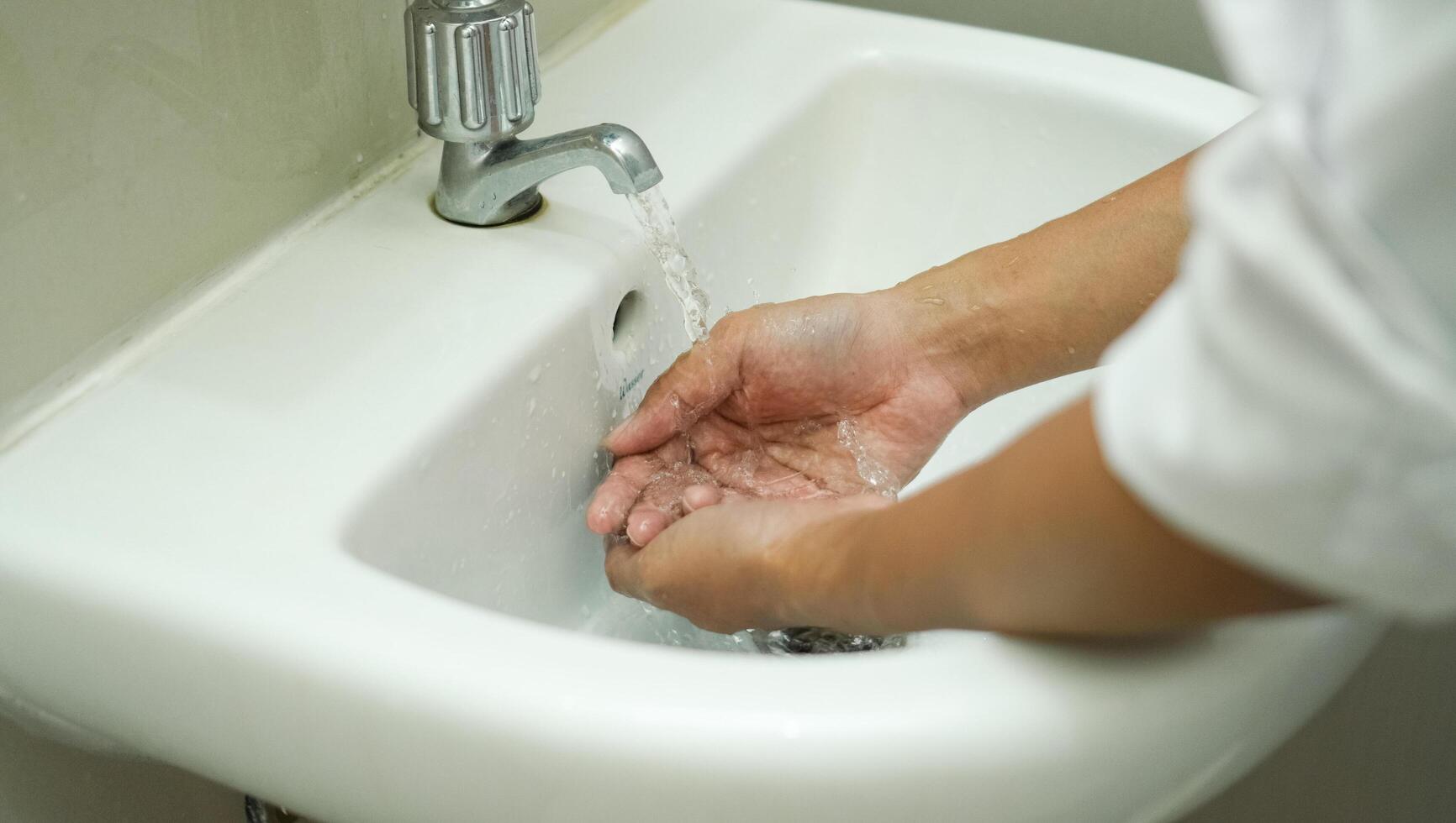 lavarsi le mani nel lavandino bianco per mantenere la mano pulita e sterile. rimuovere dai batteri attaccati. foto