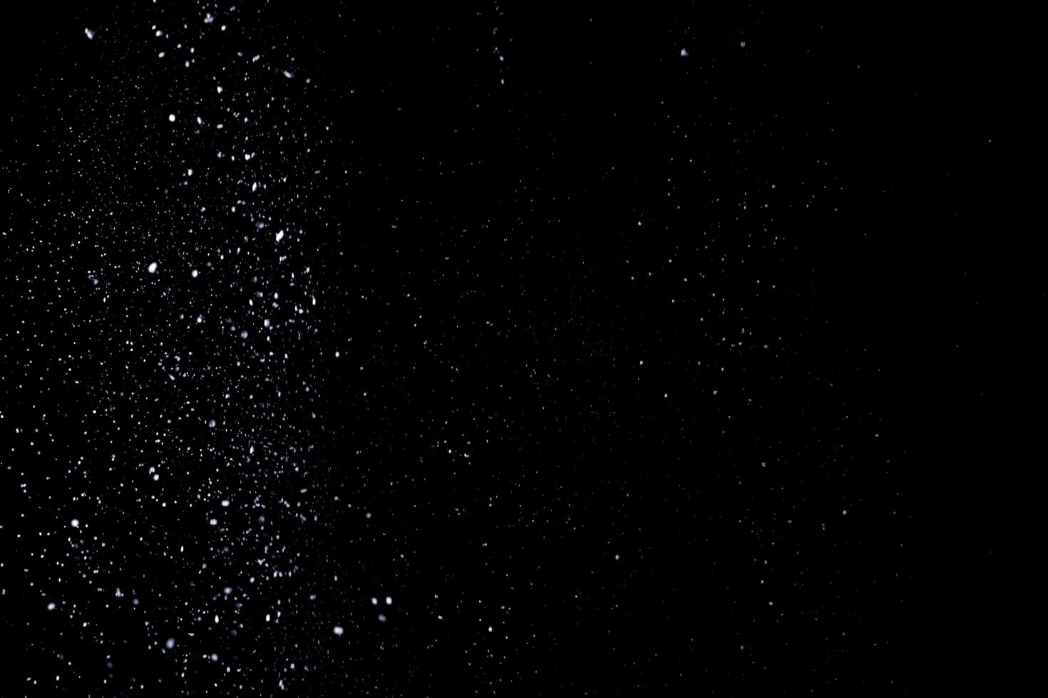 le particelle bianche su sfondo nero che rappresentano una nevicata. riprese in sovrapposizione sulla neve per dare un effetto gelido o invernale alla presentazione video. foto