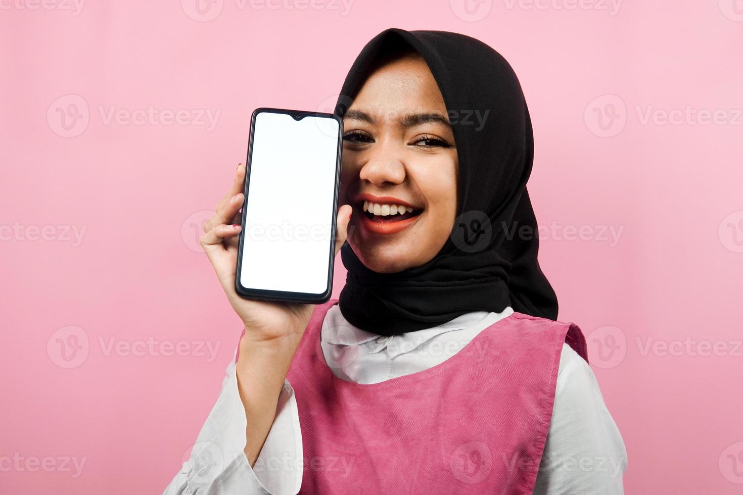 primo piano di bella e allegra giovane donna musulmana che tiene smartphone con schermo bianco o vuoto, promozione di app, promozione di qualcosa, isolato, concetto di pubblicità foto