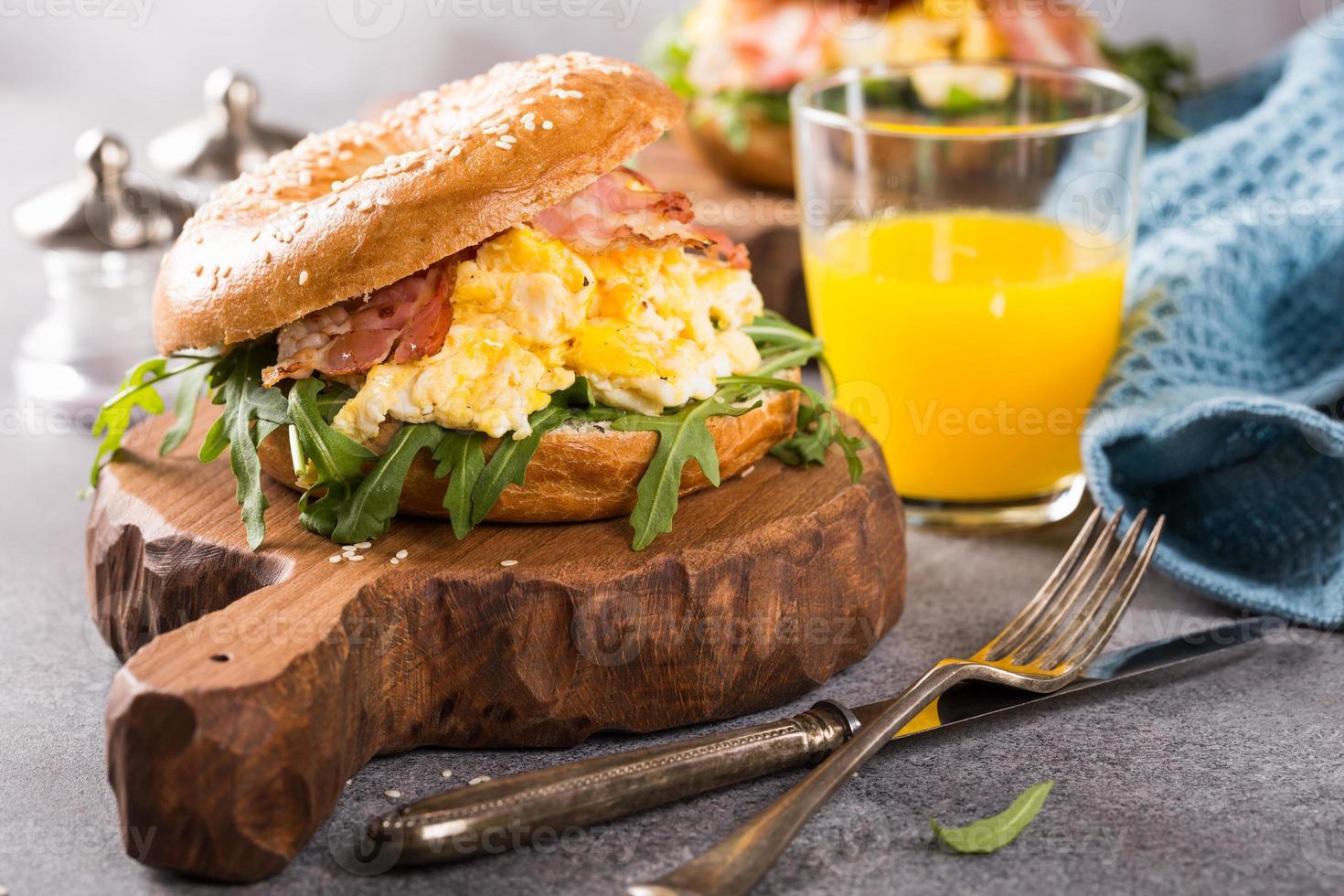 bagel con uova strapazzate, rucola e bacon fritto foto