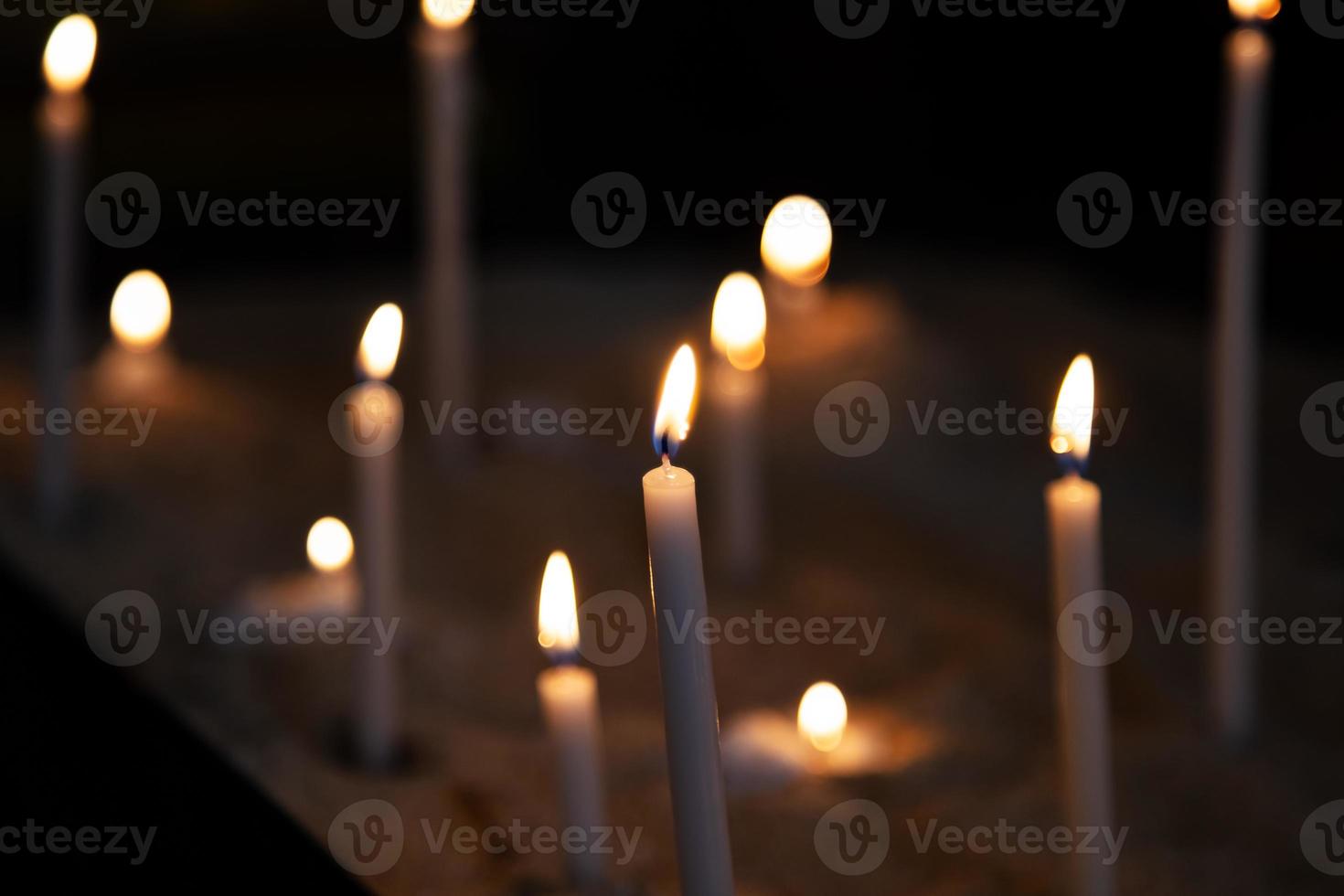 lume di candela. le candele si accendono in uno sfondo scuro. fiamme di candela nella chiesa cattolica. effetto bokeh. foto