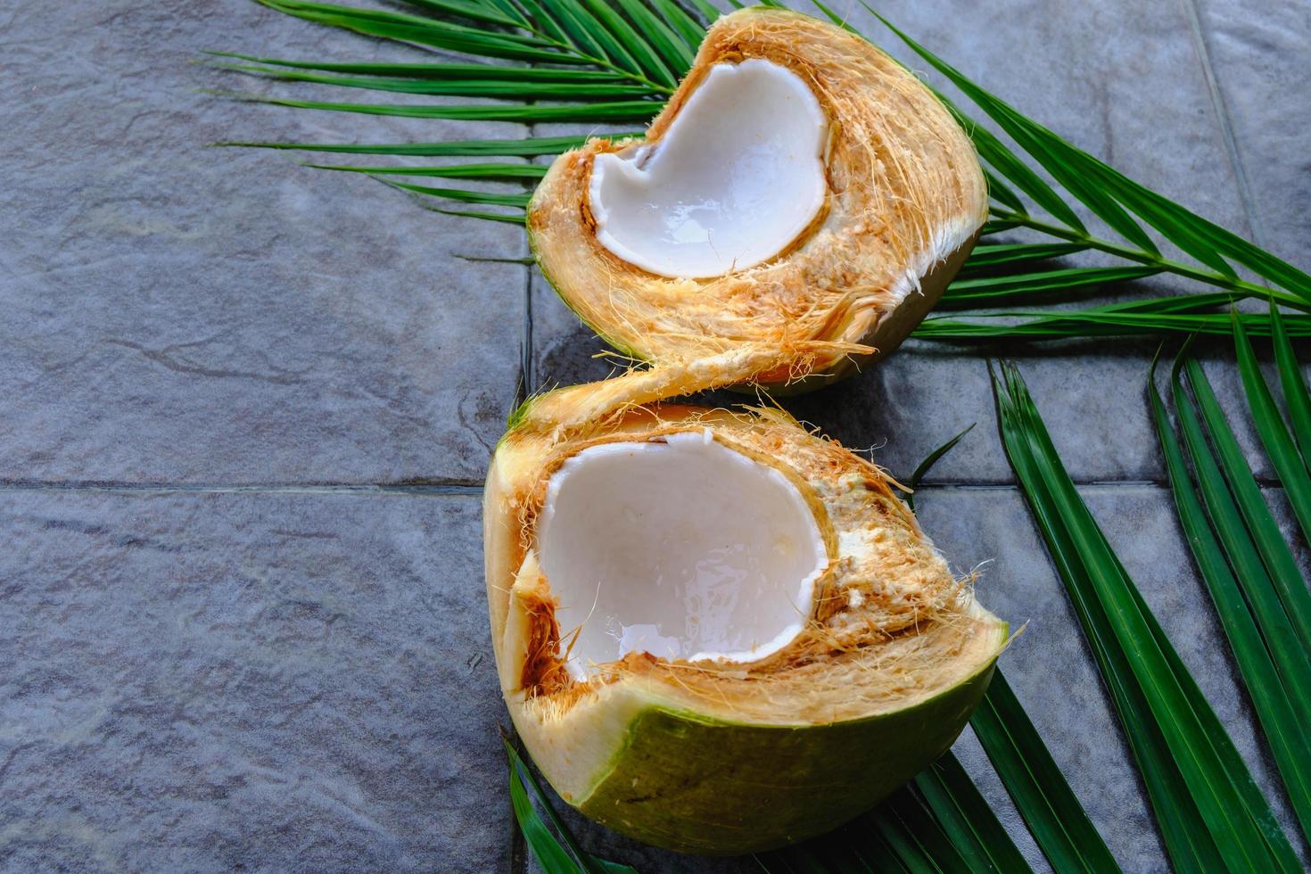 frutta fresca di cocco verde tagliata a metà e foglie di cocco foto