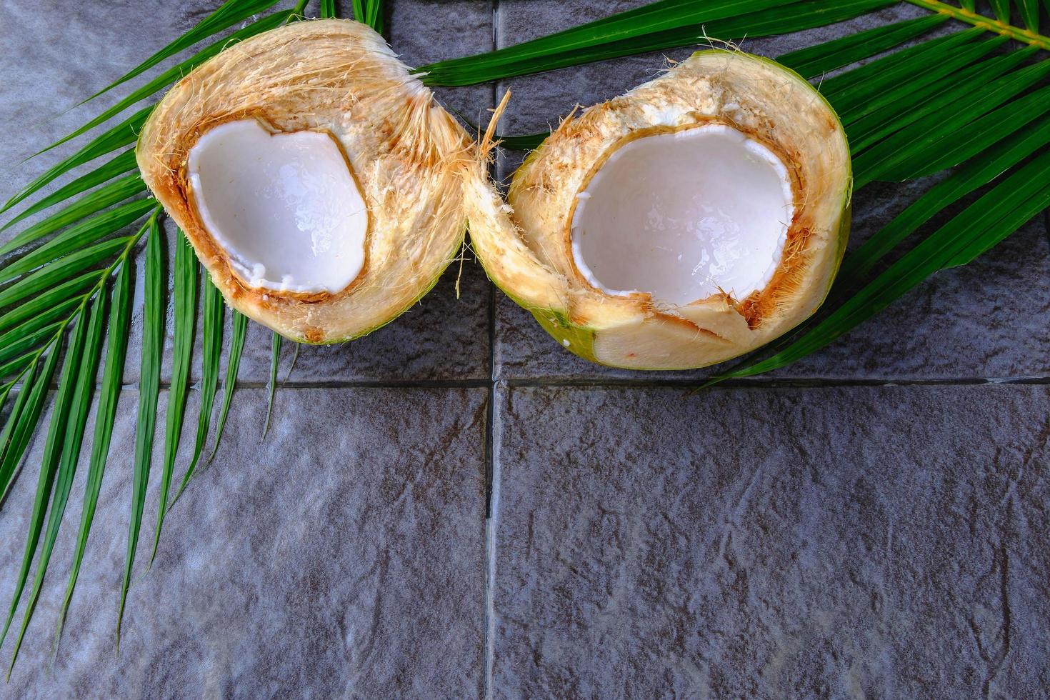 frutta fresca di cocco verde tagliata a metà e foglie di cocco foto