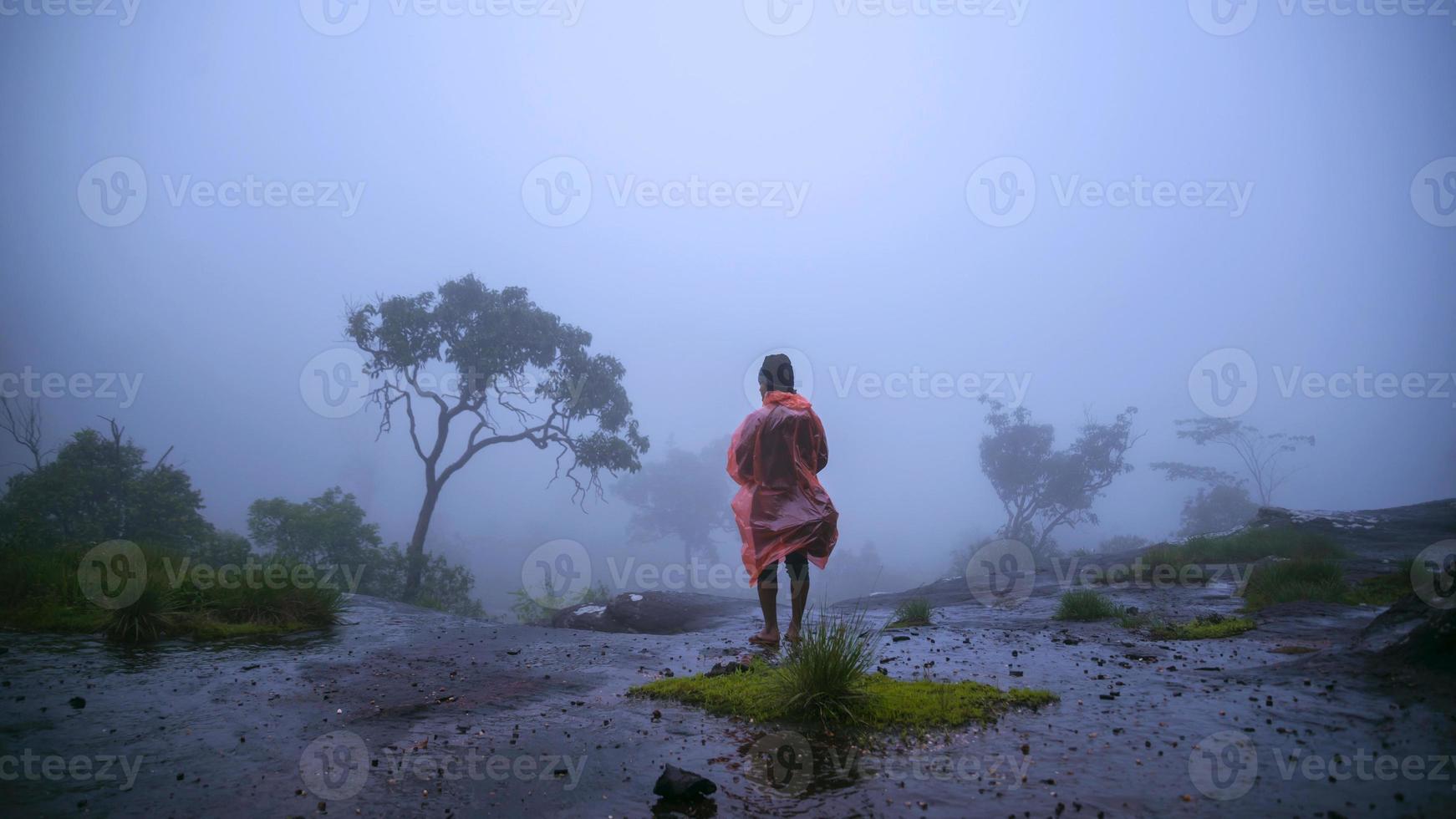 turista con impermeabile a piedi viaggio avventura natura nella foresta pluviale al parco nazionale di phu hin rong kla. viaggiare nella natura, viaggiare rilassati, viaggiare in thailandia, stagione delle piogge. foto