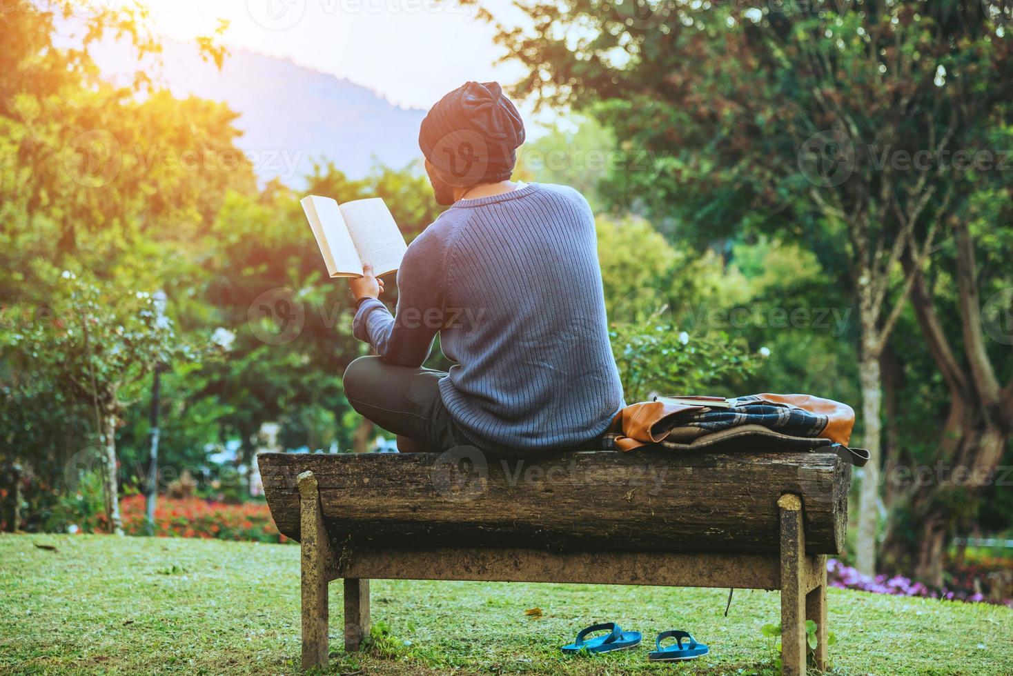 il giovane viaggia nella natura sulla montagna, è seduto e si rilassa, legge un libro nel giardino fiorito. foto