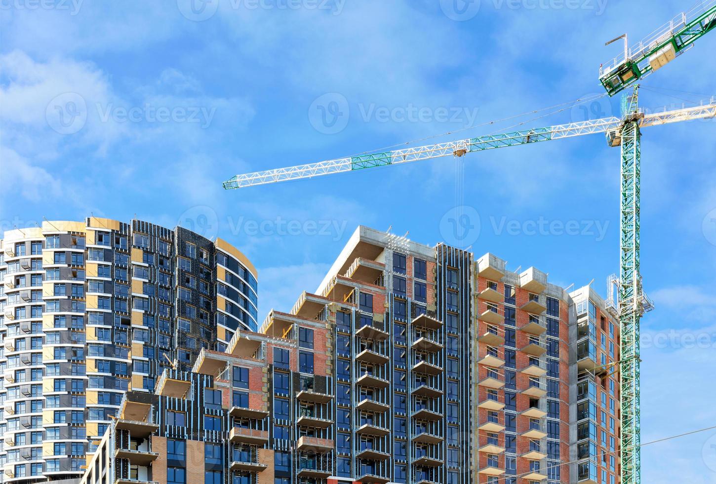 cantiere di un complesso residenziale a più piani con pavimenti a cascata contro un cielo nuvoloso blu, copia spazio. foto