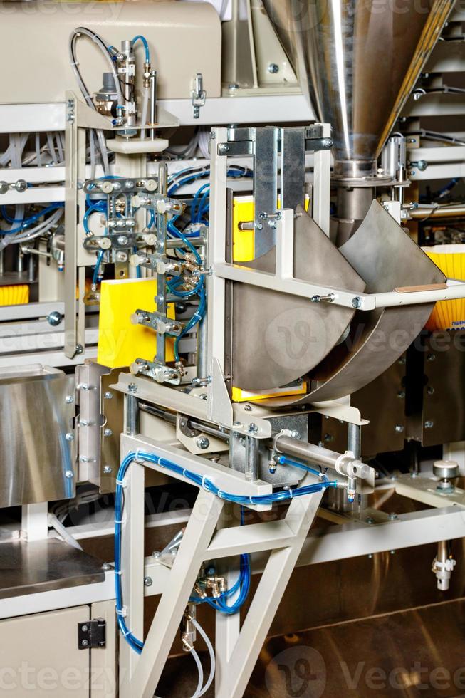 dettaglio di una linea di produzione nell'industria alimentare per il confezionamento di prodotti sfusi in sacchetti di carta gialla. foto