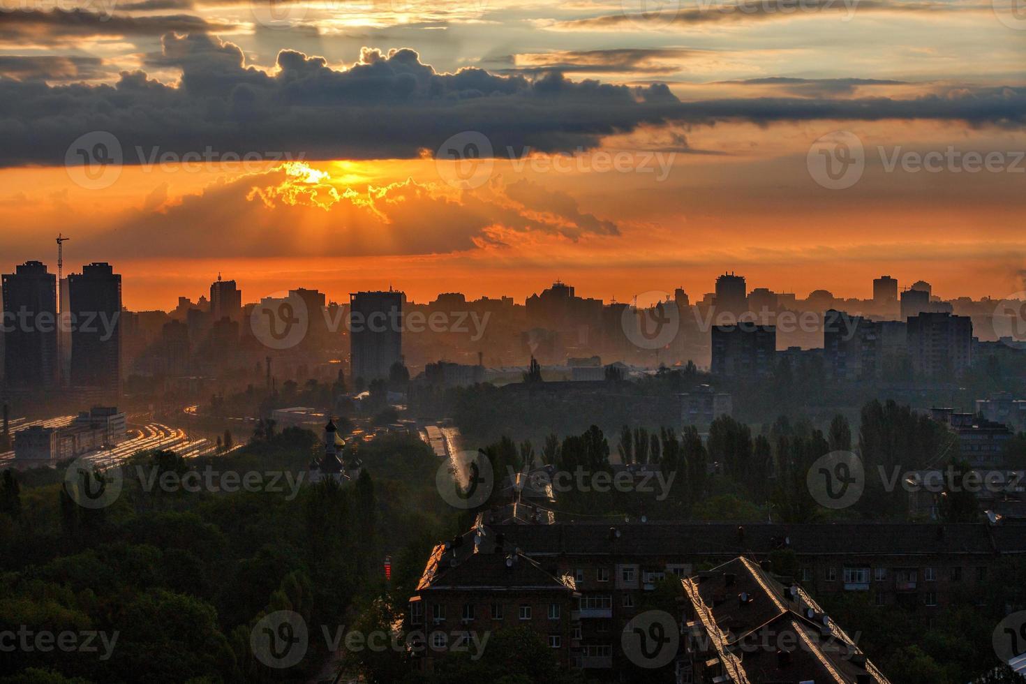 i raggi del sole sfondano le nuvole di pioggia di una nuvola all'alba e illuminano una città addormentata. foto