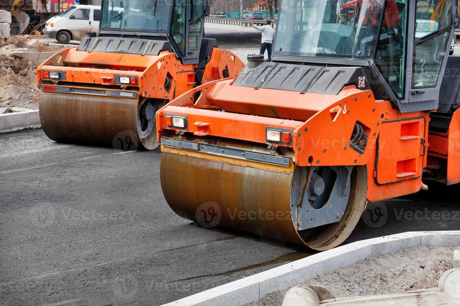 due grandi rulli vibranti compattano l'asfalto fresco di un nuovo tratto di strada. foto