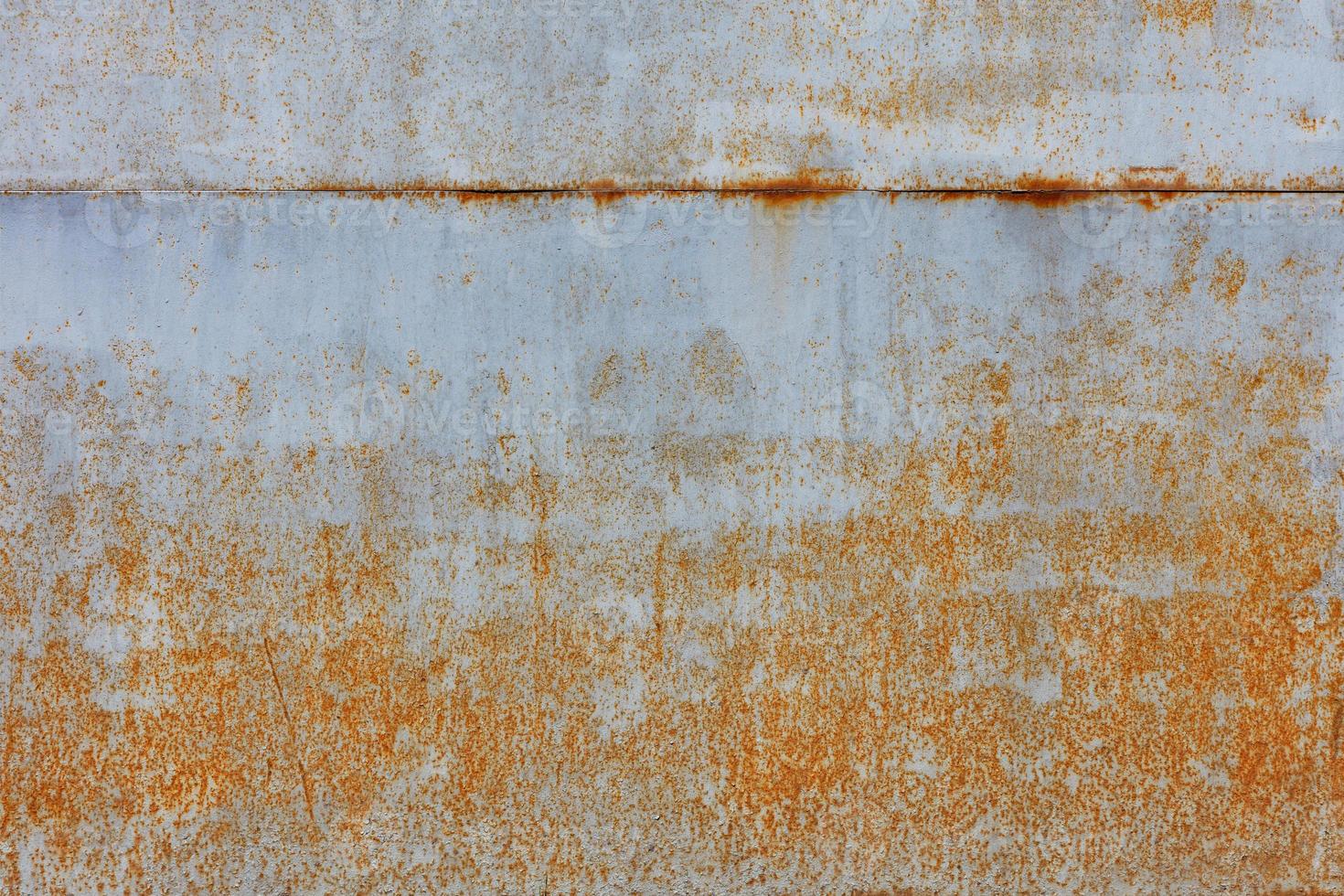 la ruggine traspare su un vecchio foglio di metallo verniciato con vernice grigia. foto