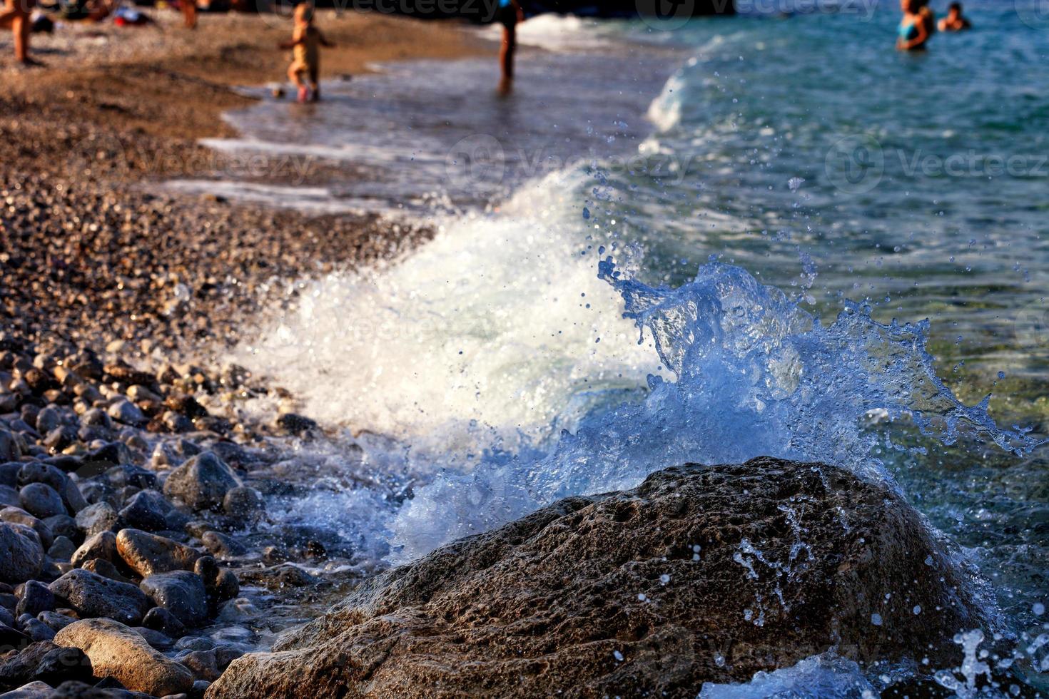 spruzzata dell'onda del mare su un grande masso sulla spiaggia del mare. foto