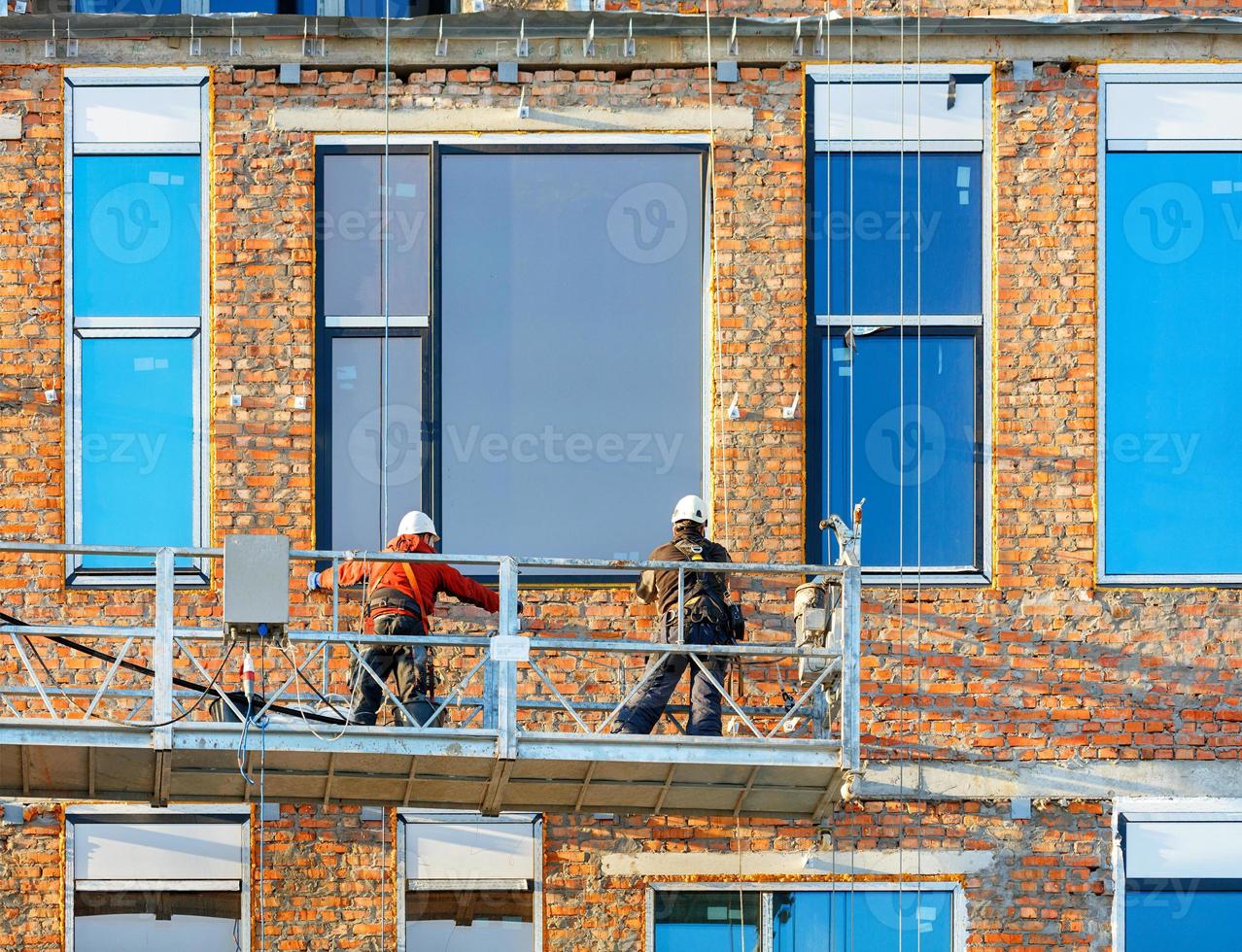 ristrutturazione della facciata e installazione di grandi finestre in un moderno edificio residenziale utilizzando un argano e una piattaforma mobile. foto