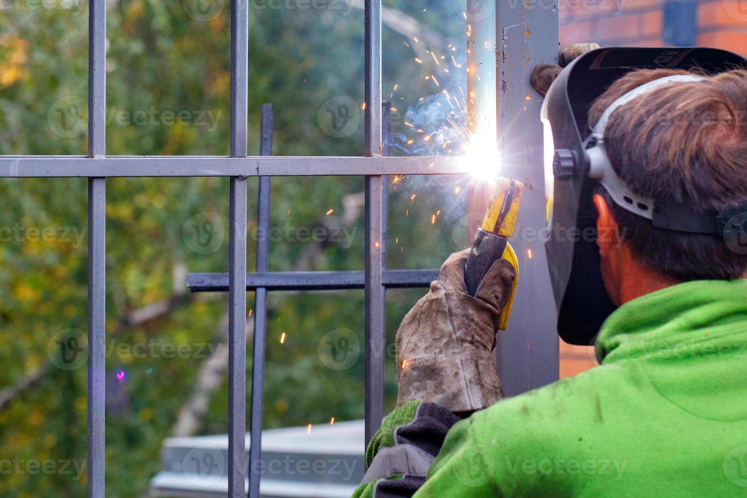 il lavoro del saldatore, un lampo luminoso dall'elettrodo durante la saldatura di una recinzione metallica. foto