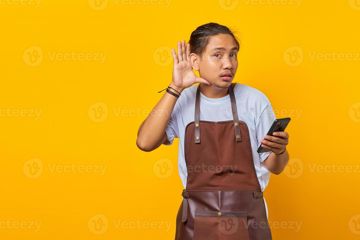 ritratto di un barista dall'aspetto serio che cerca di ascoltare una conversazione segreta e tiene in mano uno smartphone foto