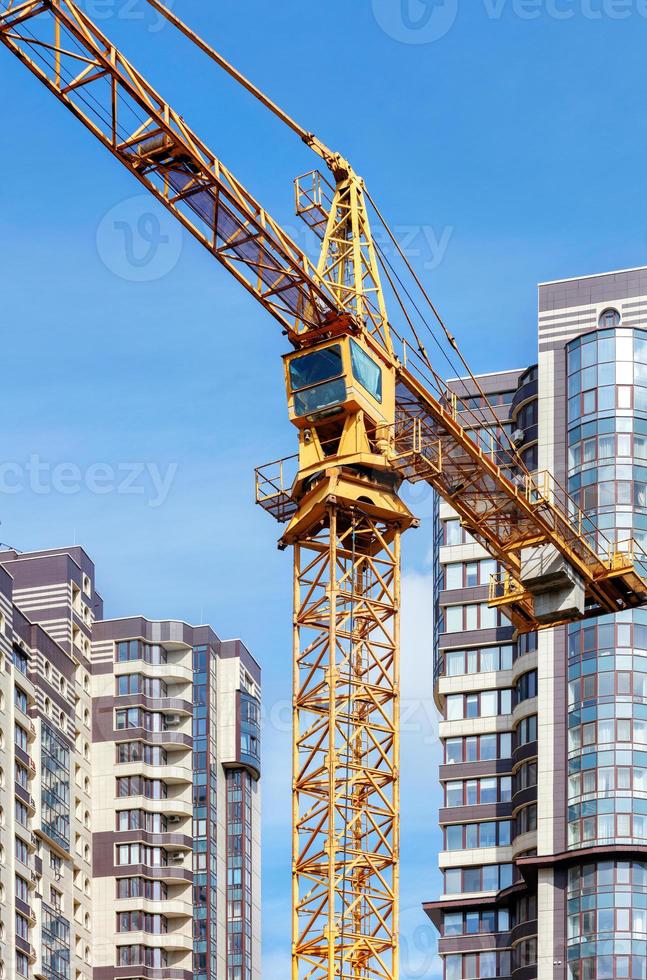 una gru a torre si erge sullo sfondo di nuovi edifici residenziali e cieli blu. foto