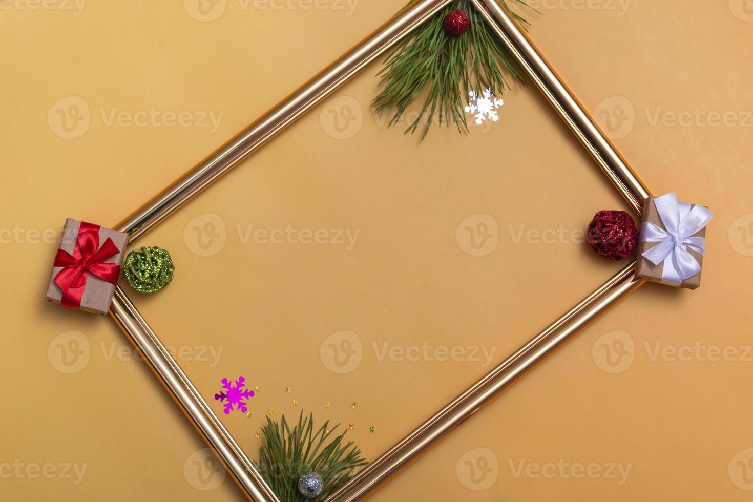 layout di capodanno su uno sfondo beige palle di natale, rami di un albero di natale, una confezione regalo e una cornice dorata, un modello di cartolina, un invito foto