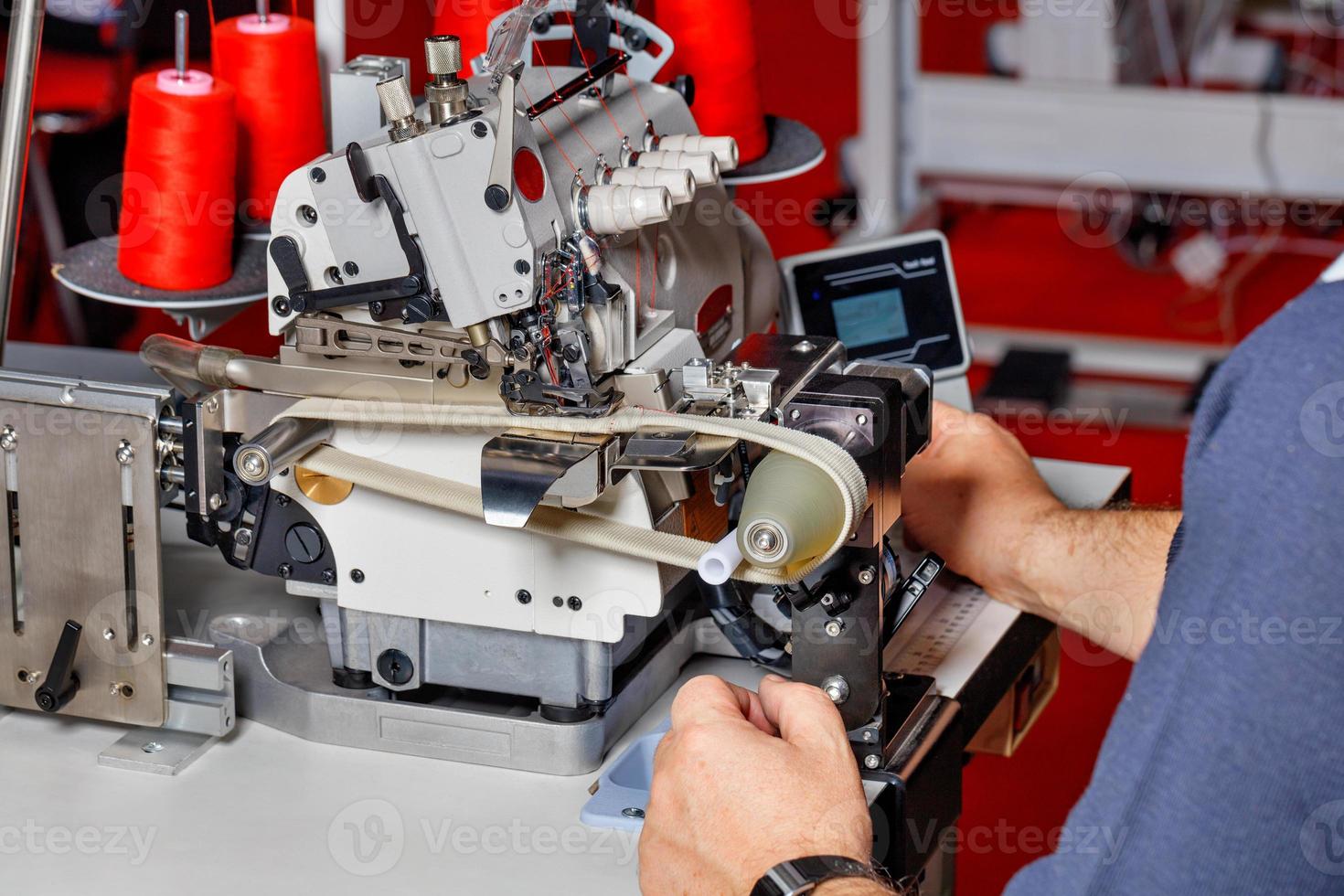 il maestro esegue la regolazione del lavoro di una moderna macchina da cucire elettrica. foto