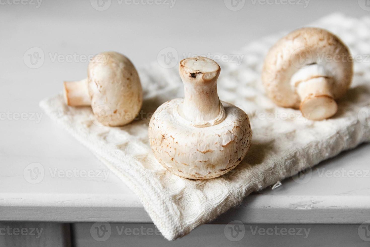 funghi prataioli sul tovagliolo da cucina su un tavolo di legno bianco foto