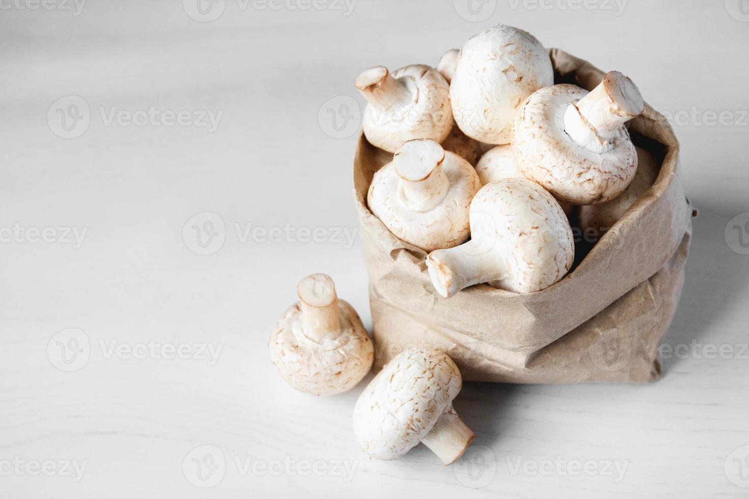 funghi champignon in sacchetto di carta su un tavolo di legno bianco foto