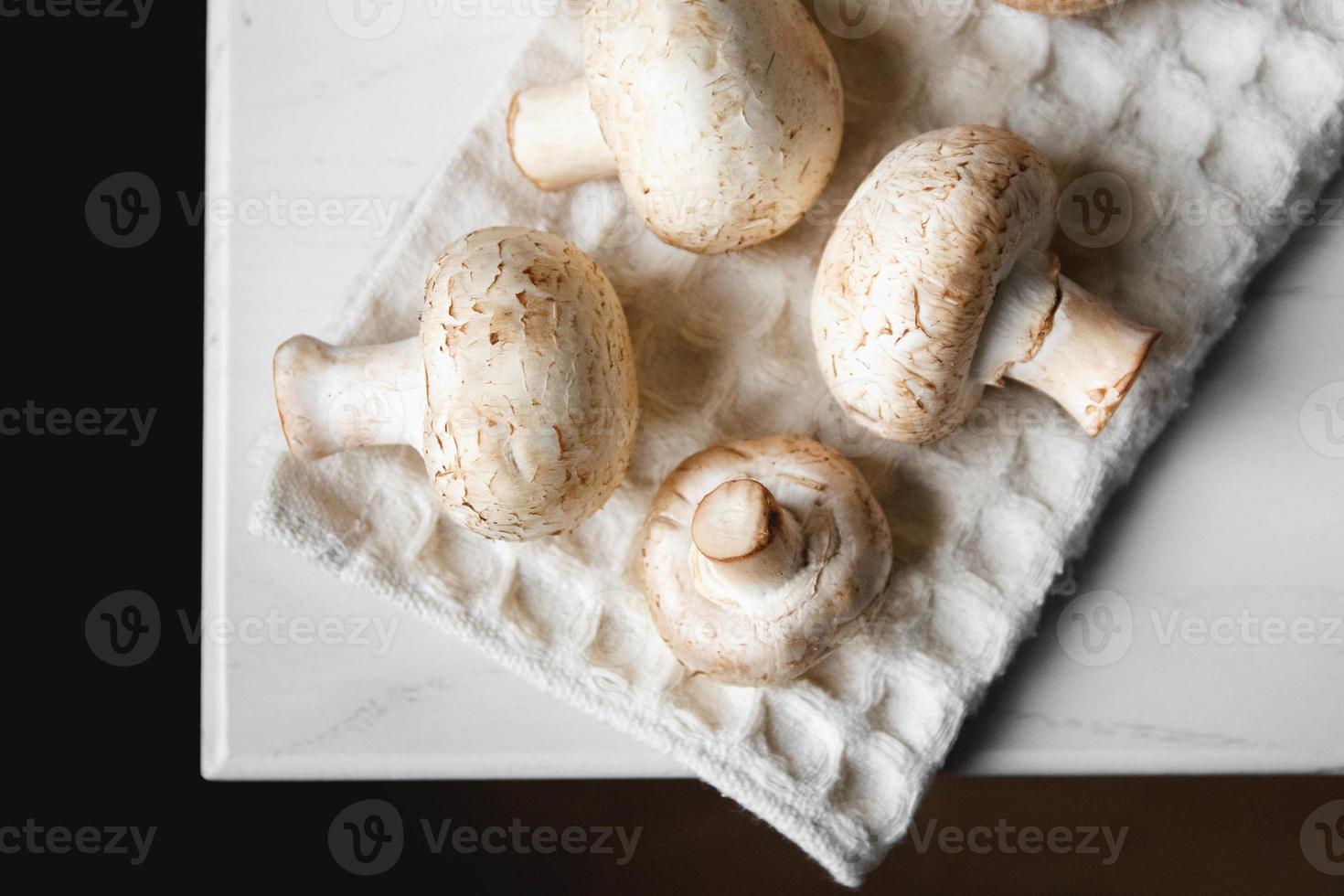 funghi prataioli sul tovagliolo da cucina su un tavolo di legno bianco foto