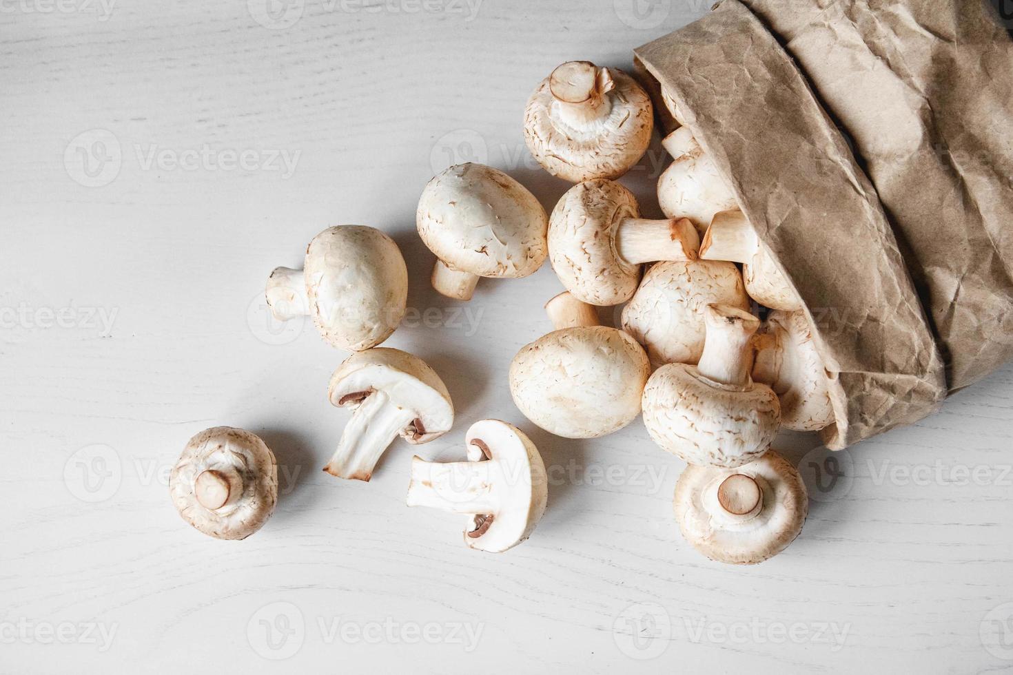funghi champignon in sacchetto di carta su un tavolo di legno bianco foto